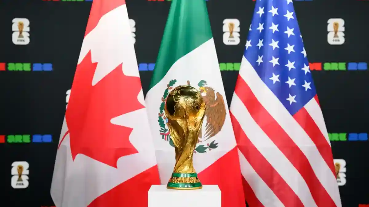 FIFA World Cup 2026 - image of the championship trophy in front of flags of the three host nations for the tournament - Canada, Mexico, and the United States (image via FIFA website)