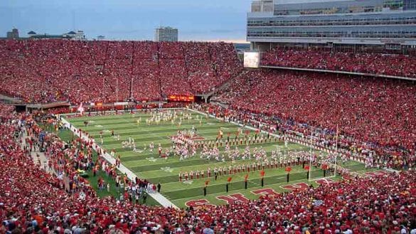 Memorial Stadium in Nebraska during a football game featuring the Cornhuskers and USC Trojans and a full capacity crowd wearing red.