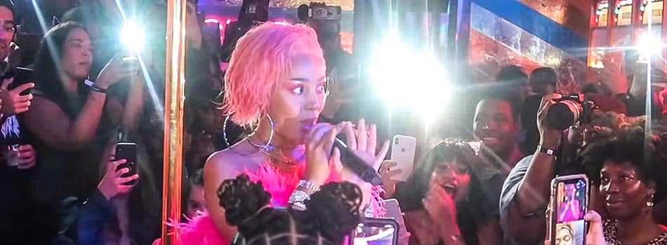 Doja Cat during a live performance among a crowd holding cell phones and filming her